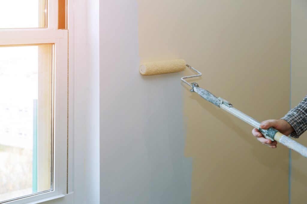 Painting male hand walls with paint roller apartment, renovating with color paint